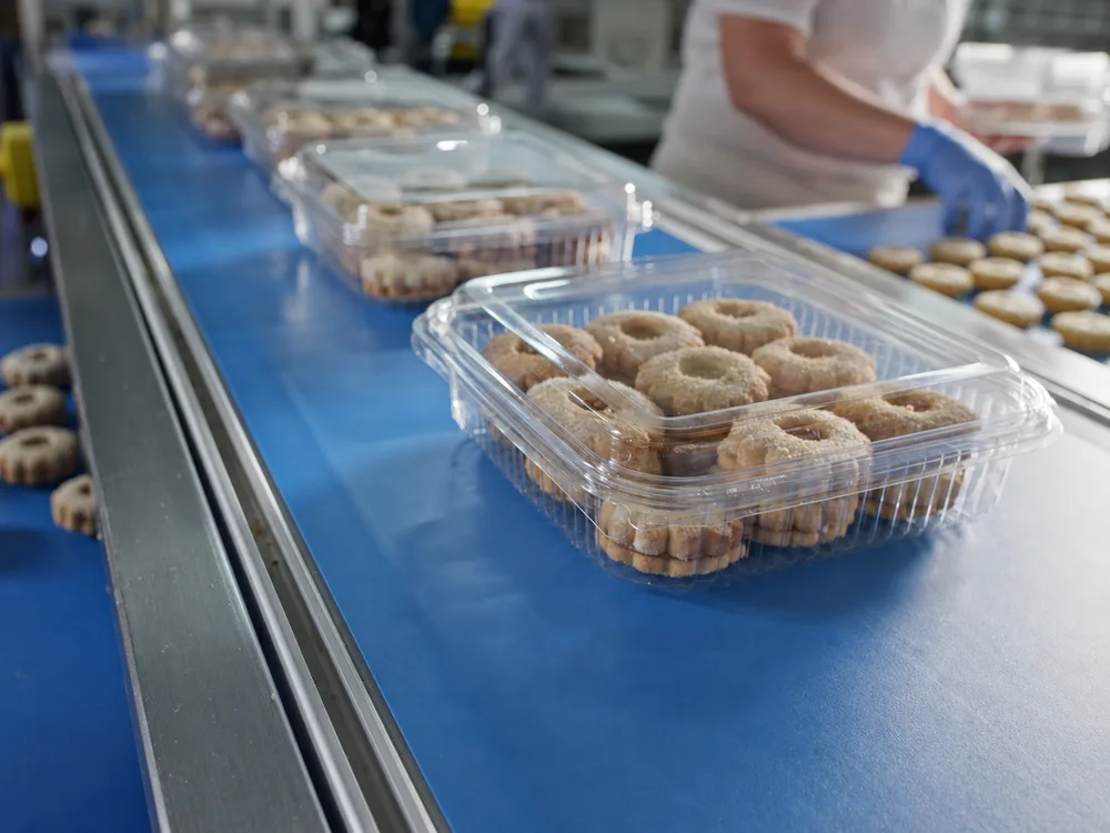 Cookies packed in clear PET bakery containers on a production line