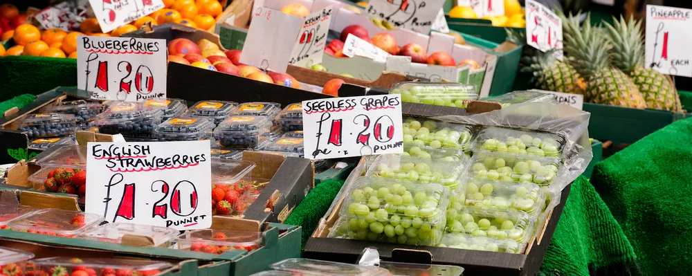 Fresh fruit punnets displayed at a market stall with various berries and fruits in clear plastic packaging