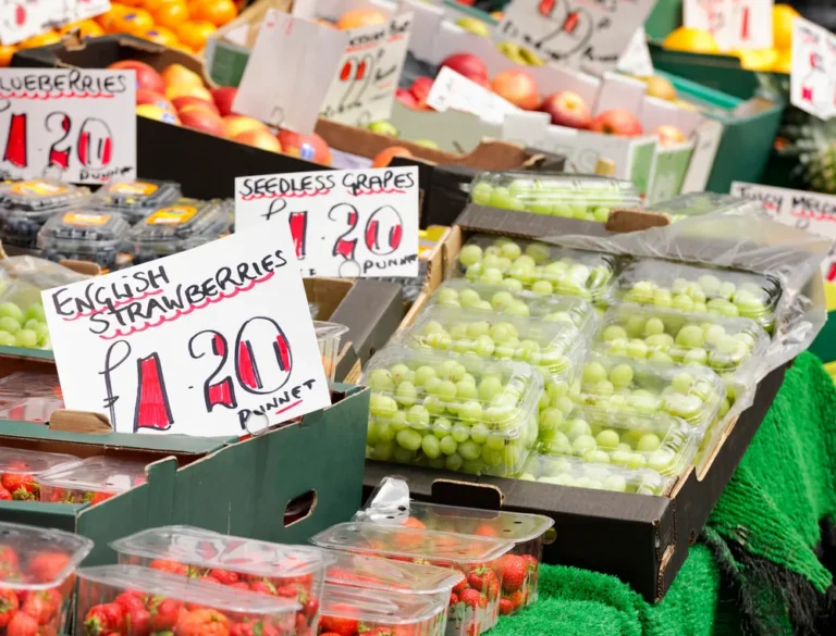 Packaged fresh fruit displayed at an outdoor market with various punnets and clamshells