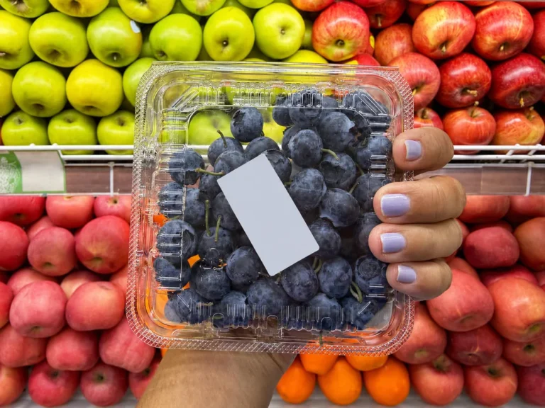Clear PET plastic grape clamshell container displayed in a supermarket fruit section showing visibility and retail presentation