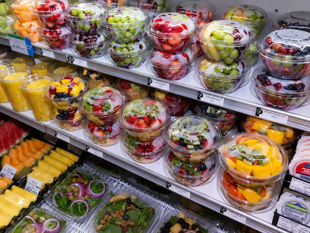 Clear PET fruit cups with fresh-cut fruit on a refrigerated retail shelf