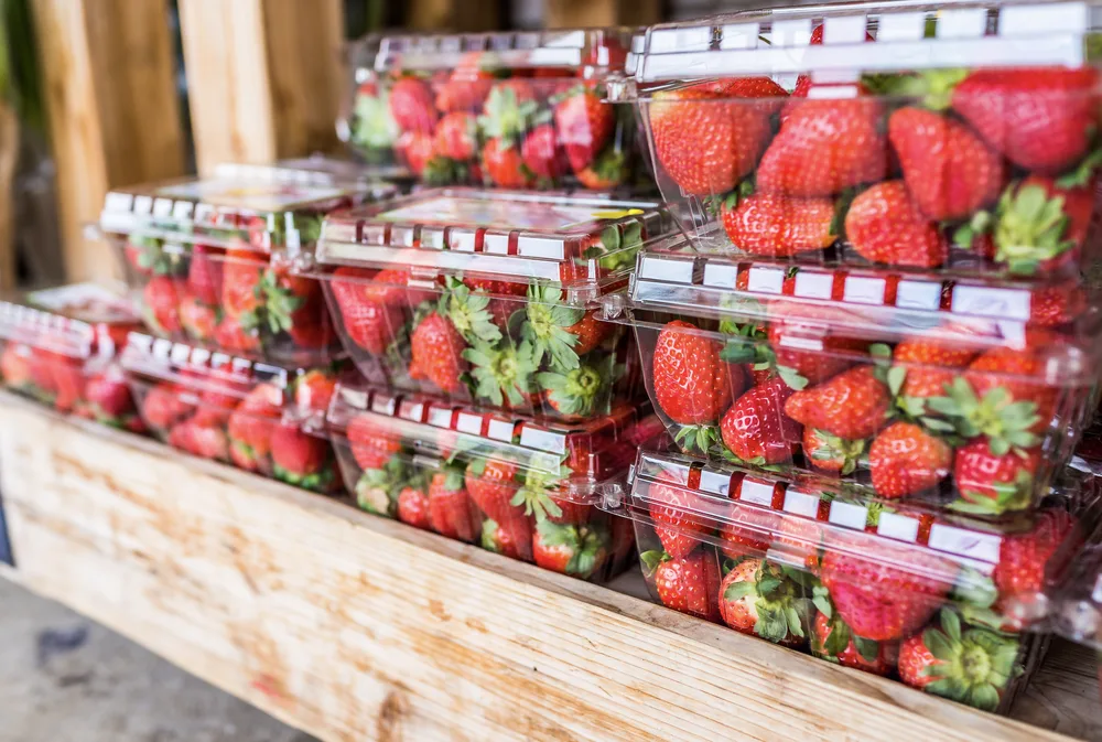 Fresh strawberries displayed in clear plastic punnets at a grocery store