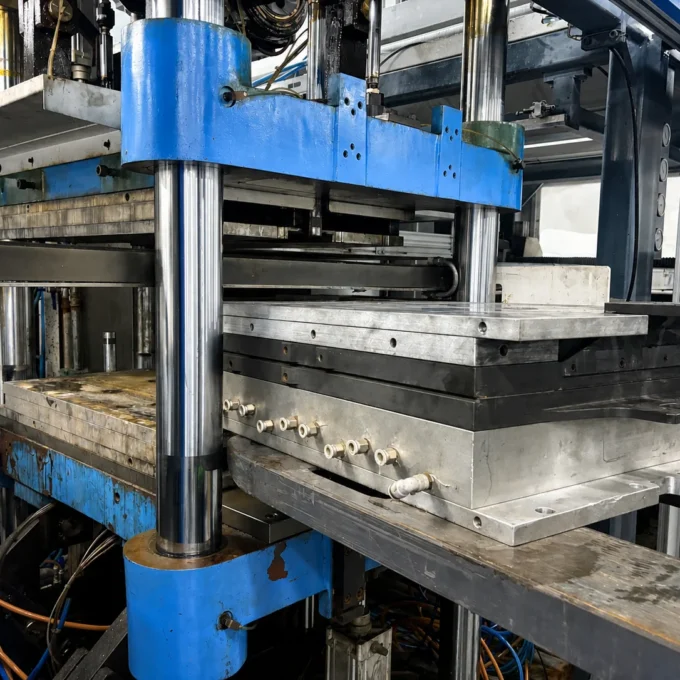 Food packaging mold loaded into a thermoforming machine for production.