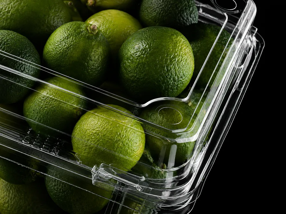 Clear PET fruit clamshell with fresh limes, reinforced edges and secure lock closure for produce packaging