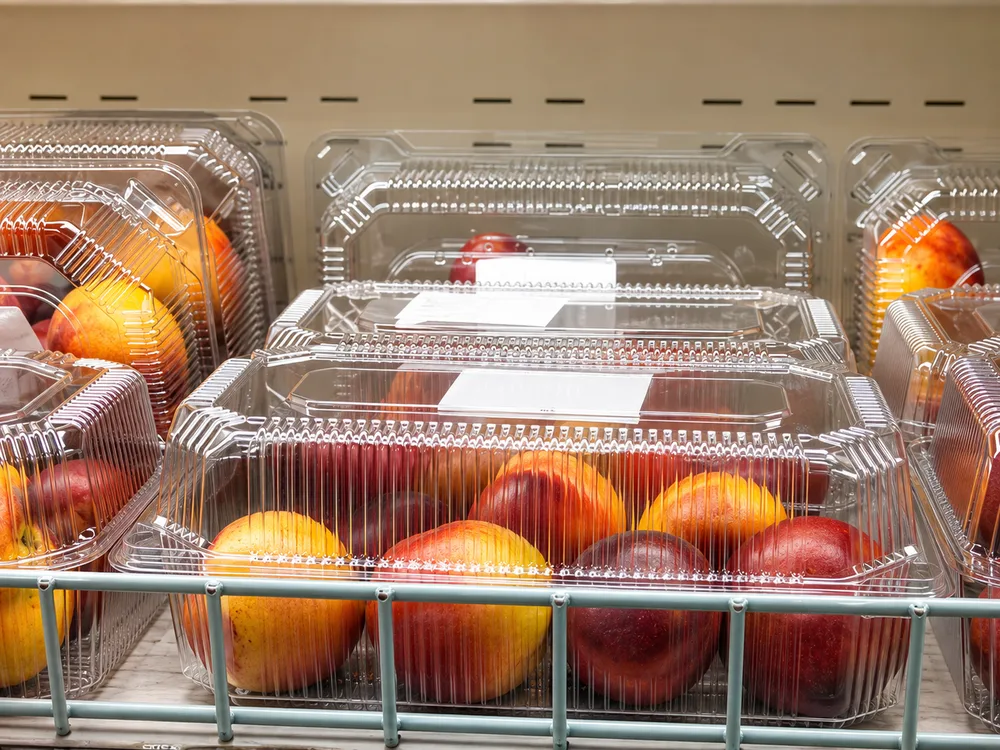 Close-up transparent PET fruit container with fresh produce showing structural details and ventilation