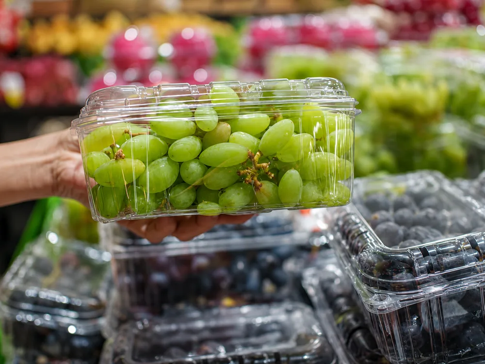 Transparent PET grape clamshell packaging in fresh produce retail display setting