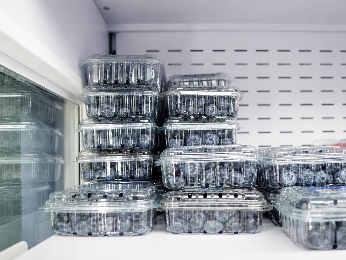 Stacks of PET fruit clamshell containers in refrigerated storage.
