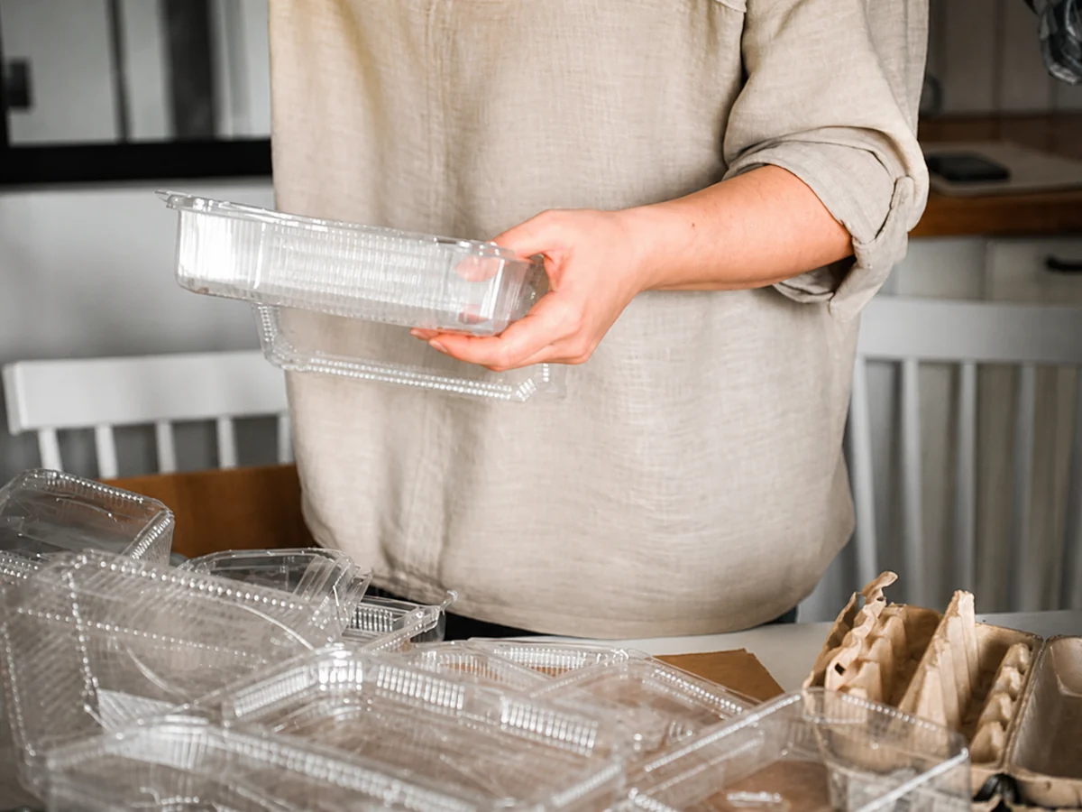 Person handling clear PET food containers for e-commerce packaging supply