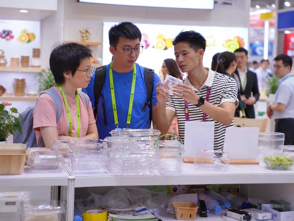 Customers reviewing clear PET food container samples before custom printing